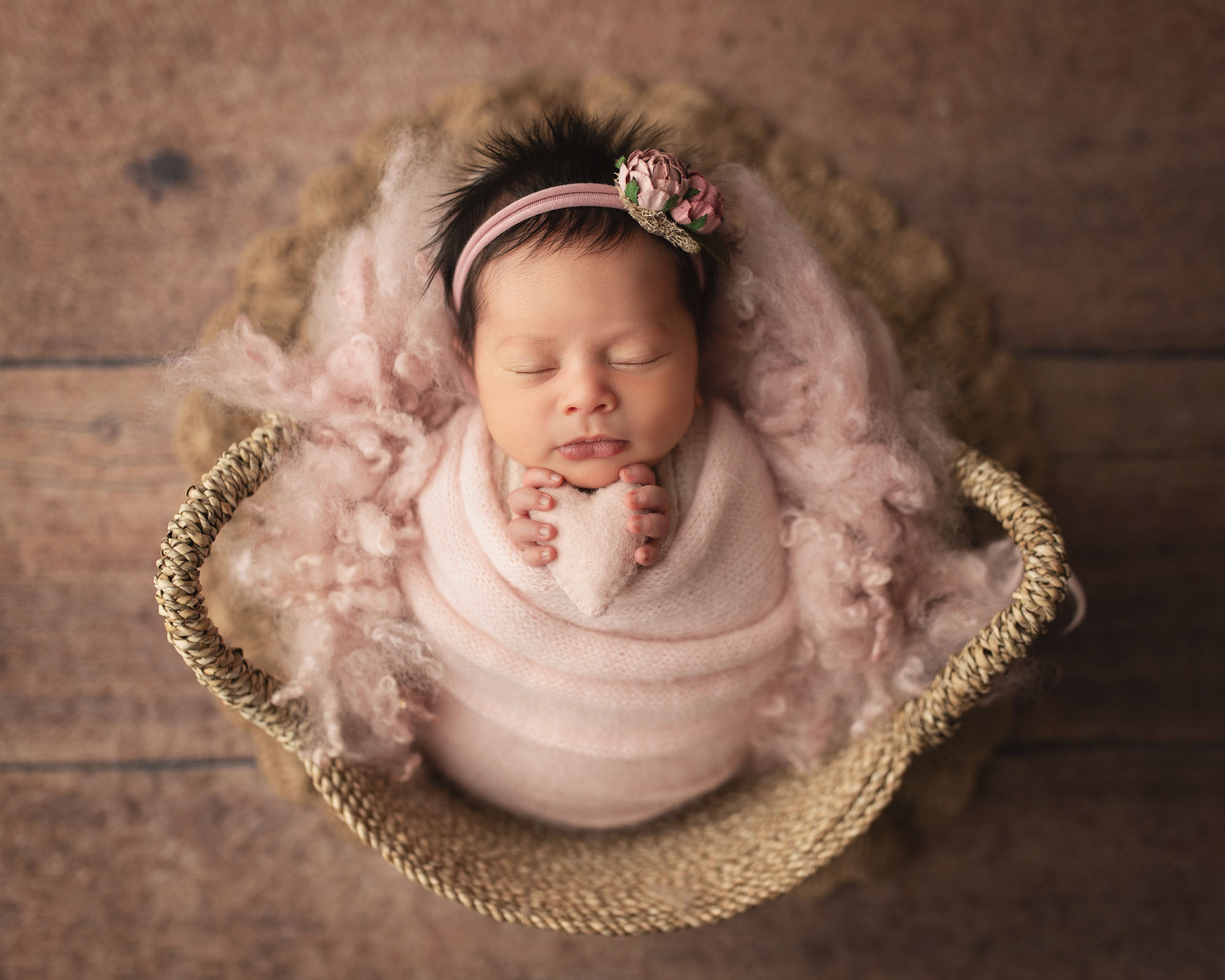 Newborn baby in a basket wrapped in pink